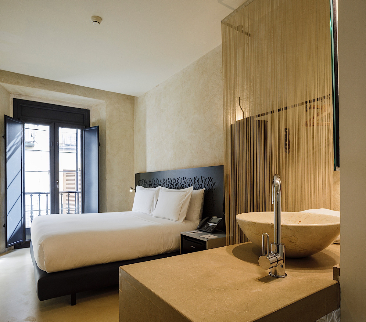 Bed and bathroom of the Superior Room at the EME Catedral Mercer Hotel