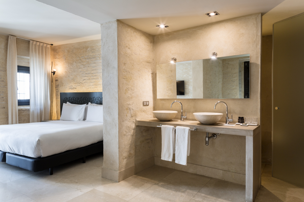 Bathroom and bed of the Suite Views at the EME Catedral Mercer hotel